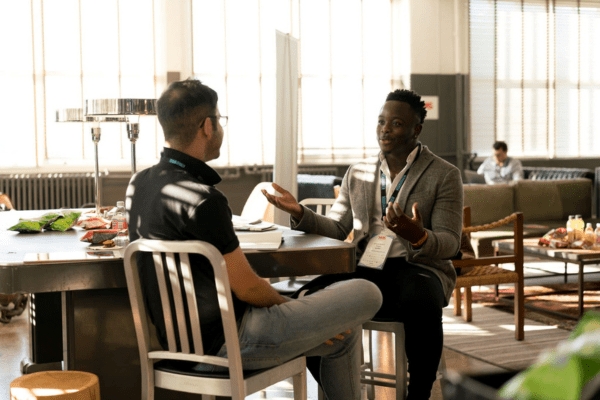 A salesperson at a networking event asking open-ended questions in sales conversations