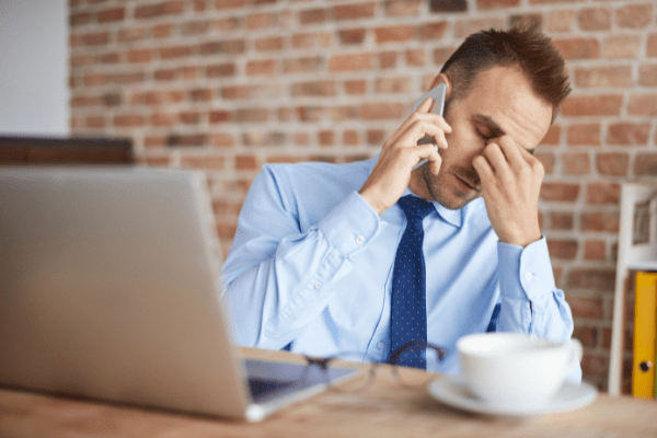 Founder at his computer having a stressful phone conversation with an unqualified client