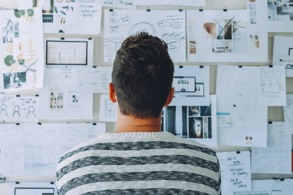 Founder looking at his vision board deciding on focusing on sales vs. marketing