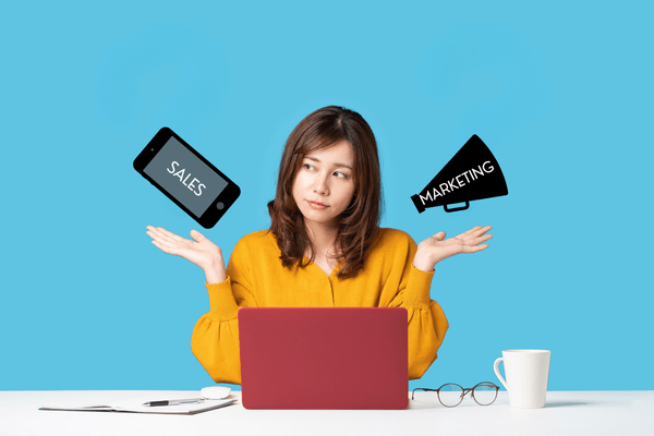 Founder sitting at a computer contemplating sales vs. marketing for her business
