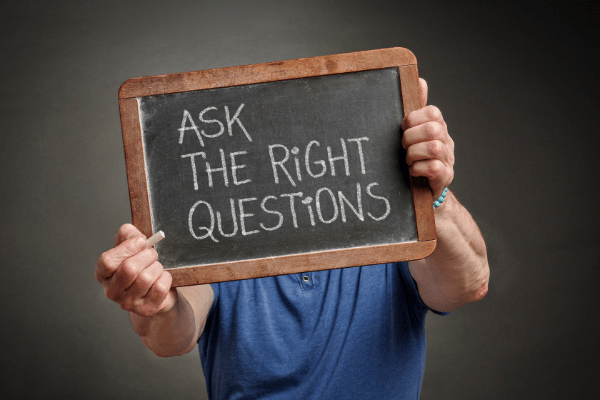 Man holding up chalkboard that says, _Ask the right questions